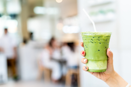 close-up hand holding iced matcha latte green tea cupの写真素材