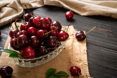 Fresh cherries in bowl  on wood backgroundの写真素材
