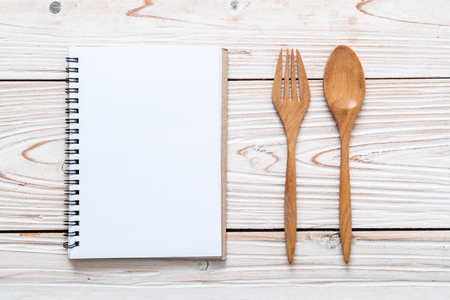 blank notebook for text note on wooden surface and wooden spoon and fork with copy sapceの写真素材