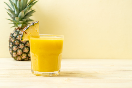 fresh pineapple smoothie glass on wood table - Healthy Drinkの写真素材