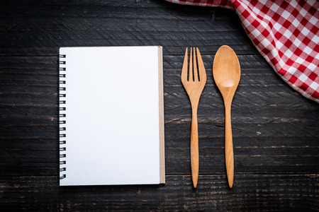 blank notebook for text note on wooden surface and wooden spoon and fork with copy sapceの写真素材