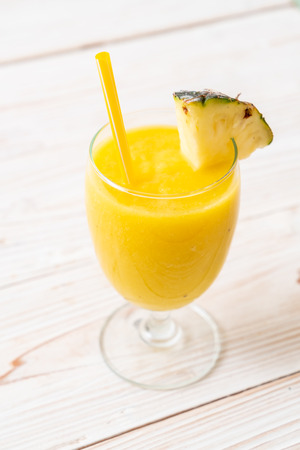 fresh pineapple smoothie glass on wood table - Healthy Drinkの写真素材