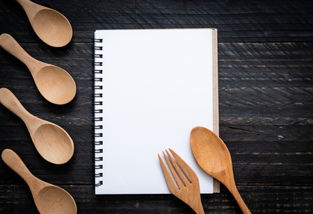 blank notebook for text note on wooden surface and wooden spoon and fork with copy sapceの写真素材