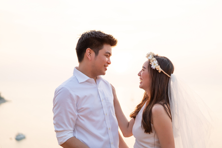 Happy young Asian couple in love having a good time with sea backgroundの写真素材