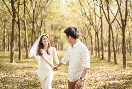 Happy Asian couple in love with tree arch at parkの写真素材