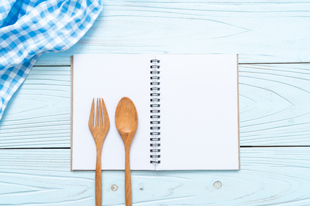 blank notebook for text note on wooden surface and wooden spoon and fork with copy sapceの写真素材