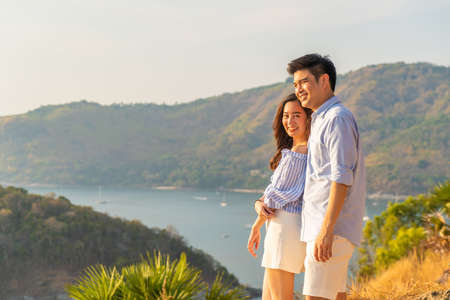 Happy young Asian couple in love having a good time in Park with sea backgroundの写真素材