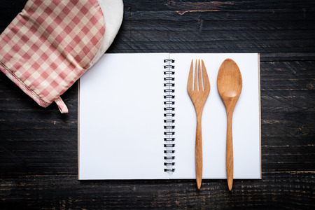 blank notebook for text note on wooden surface and wooden spoon and fork with copy sapceの写真素材