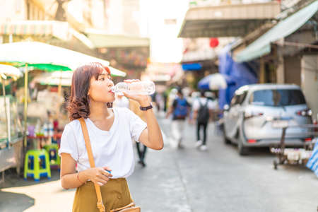 Asian female traveler holding water bottle to drink for refreshingの写真素材