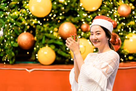 portrait of smiling beautiful young Asian woman with gift on the festive Christmas fair - vintage effect filterの写真素材