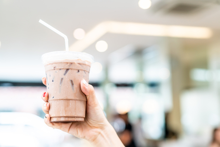 close-up hand holding iced belgian chocolate milkshake cupの写真素材