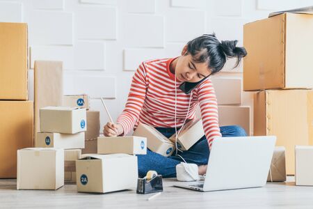 Asian Women business owner working at home with packing box on workplace - online shopping SME...