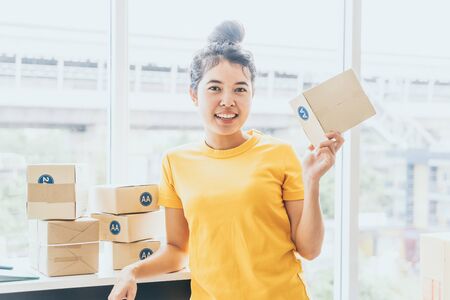 Asian Women business owner working at home with packing box on workplace - online shopping SME entrepreneur or freelance working conceptの写真素材