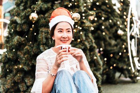 portrait of smiling beautiful young Asian woman with gift on the festive Christmas fair - vintage effect filterの写真素材