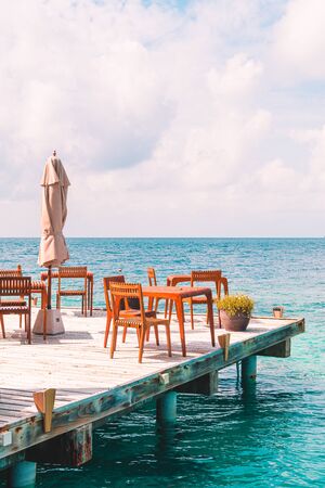 empty outdoor wood table and chair with sea view background in Maldivesの写真素材