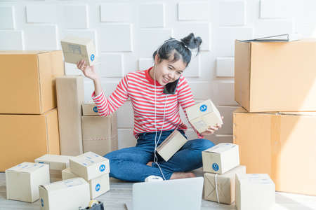 Asian Women business owner working at home with packing box on workplace - online shopping SME entrepreneur or online selling conceptの写真素材