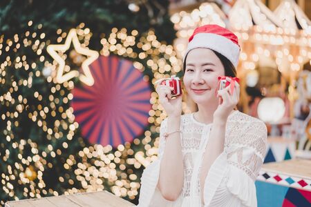 portrait of smiling beautiful young Asian woman with gift on the festive Christmas fair - vintage effect filterの写真素材