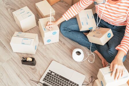Asian Women business owner working at home with packing box on workplace - online shopping SME...