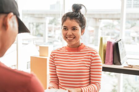 Asian woman receiving delivery package - selective focus pointの写真素材