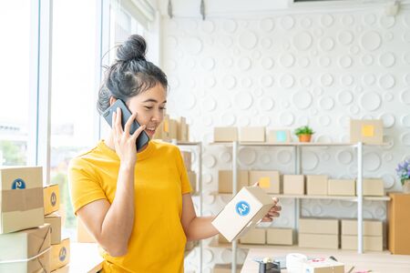 Asian Women business owner working at home with packing box on workplace - online shopping SME entrepreneur or freelance working conceptの写真素材