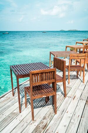 empty outdoor wood table and chair with sea view background in Maldivesの写真素材