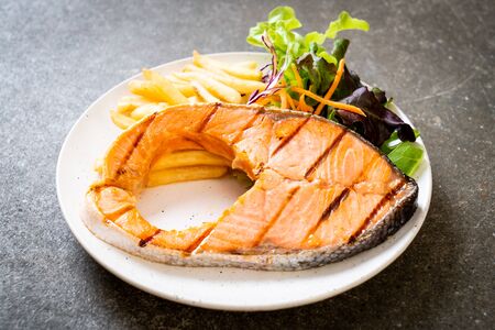 grilled salmon steak fillet with vegetable and french fries on plateの写真素材