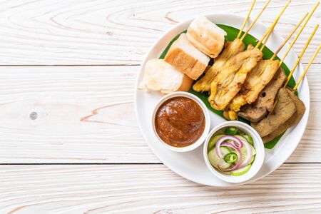 Pork Satay and Liver Satay with Bread and Peanut Sauce  and pickles which are cucumber slices and onions in vinegarの写真素材