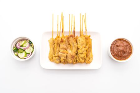 Pork satay - Grilled pork served with peanut sauce or sweet and sour sauce - isolated on white backgroundの写真素材