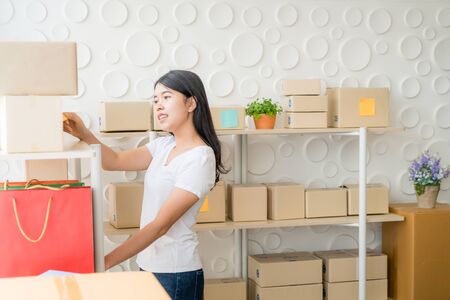 Asian Women business owner working at home with packing box on workplace - online shopping SME entrepreneur or freelance working conceptの写真素材
