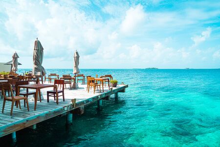 empty outdoor wood table and chair with sea view background in Maldivesの写真素材