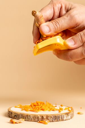 hand slicing fresh turmeric on tableの写真素材