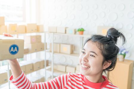 Asian Women business owner working at home with packing box on workplace - online shopping SME entrepreneur or online selling conceptの写真素材
