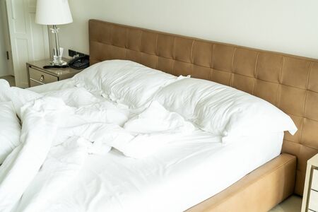 Messy bed with white pillow and blanket on bed unmade