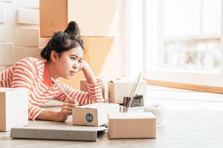 Asian Women business owner working at home with packing box on workplace - online shopping SME entrepreneur or online selling conceptの写真素材