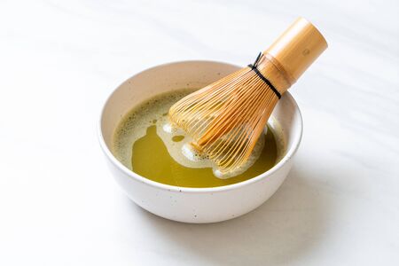 hot matcha green tea cup with green tea powder and bamboo whisk