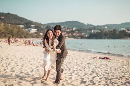 Happy Asian couple going honeymoon travel on tropical sand beach in summerの写真素材