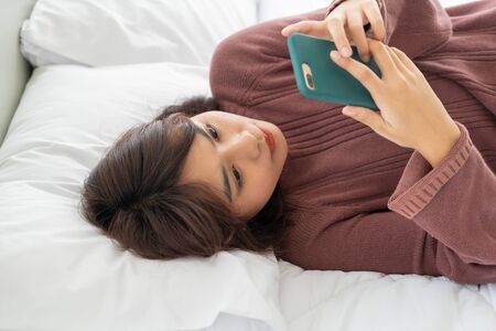 beautiful Asian women playing smartphone on bed