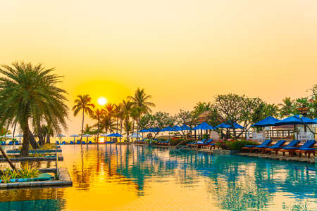 beautiful palm tree with umbrella chair pool in luxury hotel resort at sunrise times - holiday and vacation conceptのeditorial素材