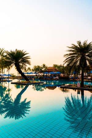 beautiful palm tree with umbrella chair pool in luxury hotel resort at sunrise times - holiday and vacation conceptのeditorial素材