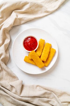 crispy fried fish fingers with breadcrumbs served on plate with ketchupの写真素材