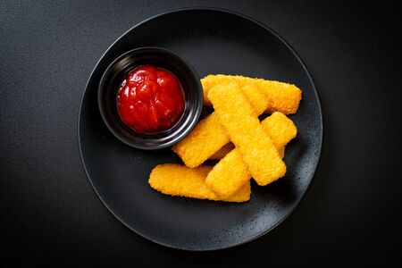 crispy fried fish fingers with breadcrumbs served on plate with ketchupの写真素材