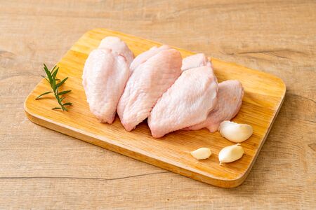 fresh raw middle chicken wings on wooden board with ingredientsの写真素材
