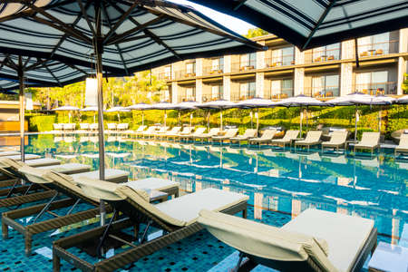Umbrella and pool bed around outdoor swimming pool in hotel resort for travel holiday vacation...