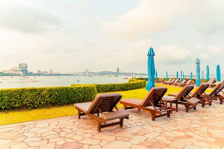 chair pool or bed pool and umbrella around swimming pool with sea beach background at Pattaya in...