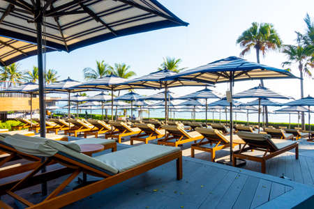 Beautiful luxury umbrella and chair around outdoor swimming pool in hotel and resort with coconut palm tree  for travel and vacation conceptのeditorial素材