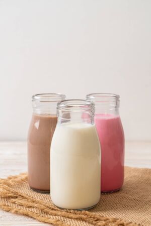 Collection of beverage chocolate milk, pink milk and fresh milk in bottle on wood tableの写真素材