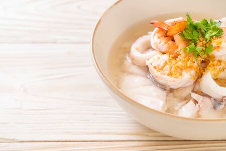 porridge or boiled rice soup with seafood (shrimps, squid and fish) bowlの写真素材