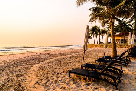 umbrella chair beach with palm tree and sea beach at sunrise times - vacation and holiday conceptの写真素材
