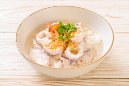 porridge or boiled rice soup with seafood (shrimps, squid and fish) bowlの写真素材