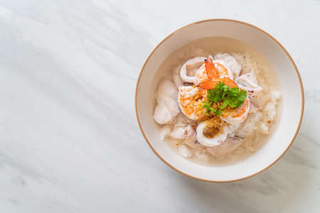 porridge or boiled rice soup with seafood (shrimps, squid and fish) bowlの写真素材